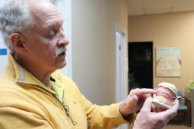Dr. William Hartman explaining dental implant-supported dentures to a patient