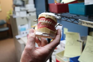 Dr. Hartman from Dr. Hartman Dentistry & Associates in Bonner Springs, KS holding up a set of dentures that he has created for a patient
